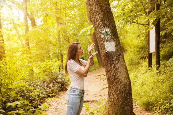 Verwirrt junge Frau betrachten ein Schild im Wald - Foto, Bild