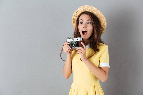 Surprised pretty girl in hat holding vintage camera - Foto, Imagen