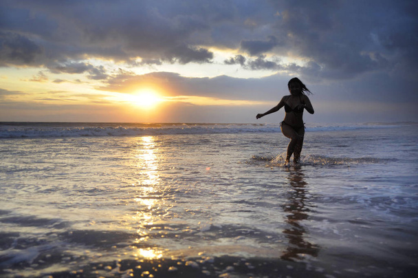 Silhouette of young beautiful and sexy asian woman running free and happy having fun at sunset beach in Bali  - Foto, Bild