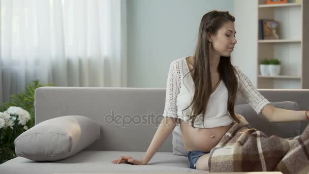 Young pregnant lady putting herself down to rest, holding teddy bear, future kid - Imágenes, Vídeo
