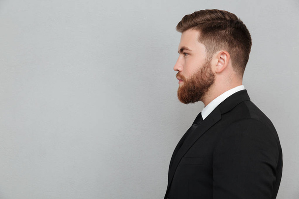 Portrait of a young bearded man in suit looking forward - 写真・画像