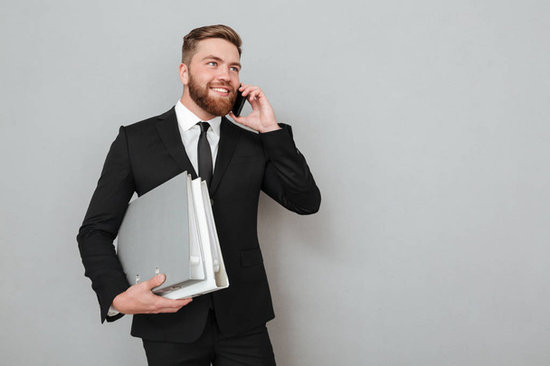 Smiling bearded man in suit talking on the smartphone - Photo, image