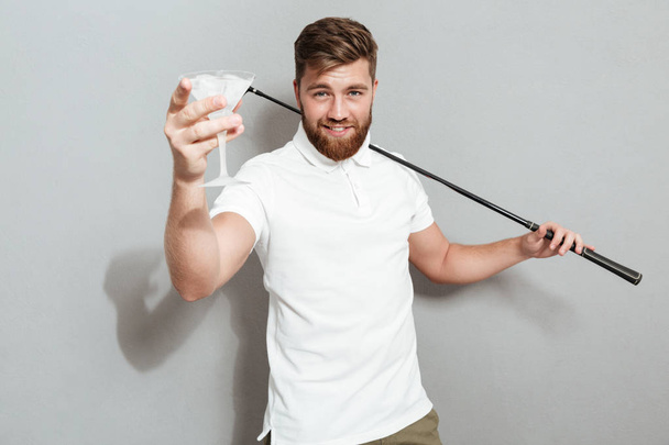 Smiling golfer posing with cocktail and looking at the camera - Фото, изображение