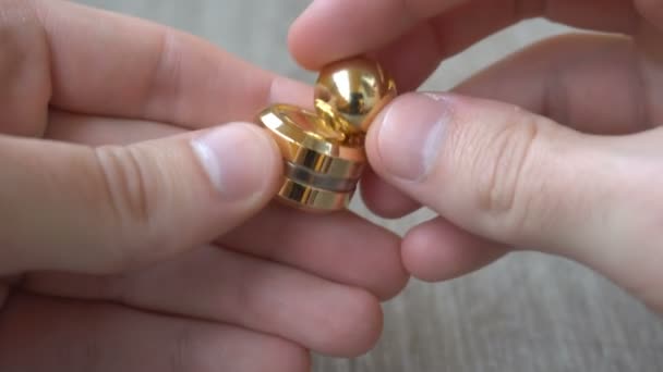 new gold fidget Orbiter,spinning in the hand of a young man on gray background - Filmagem, Vídeo