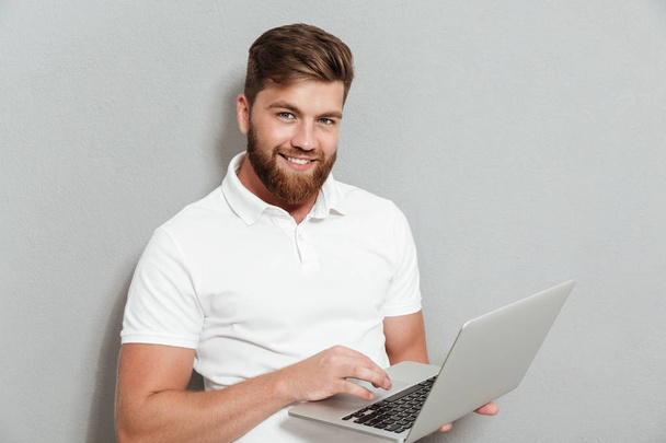 Smiling bearded man using laptop computer - Foto, Imagem