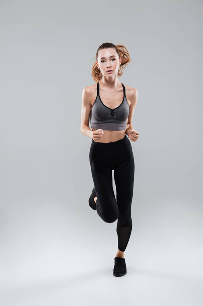 Full length portrait of a young woman in sportswear running - Fotó, kép