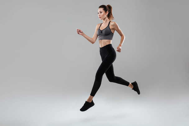 Side view full length portrait of a young fitness woman running - Photo, Image