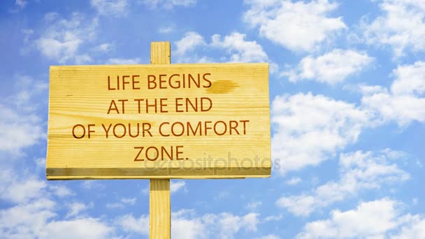 Motivational quote to create future. Life begins at the end of your comfort zone. Words on a wooden sign against time lapse clouds in the blue sky. - Footage, Video