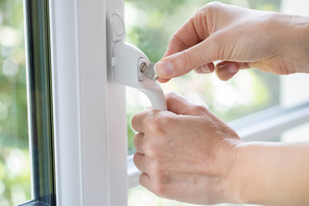 Close Up Of Woman Turning Key In Window Lock - Foto, Bild