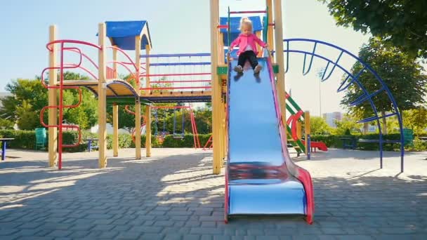 Movimiento lento: niña de tres años baja del tobogán en el patio del parque
. - Metraje, vídeo