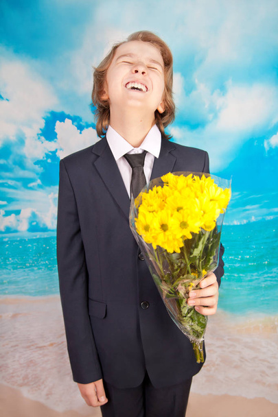 niño emocional con flores amarillas sobre fondo azul marino
 - Foto, imagen
