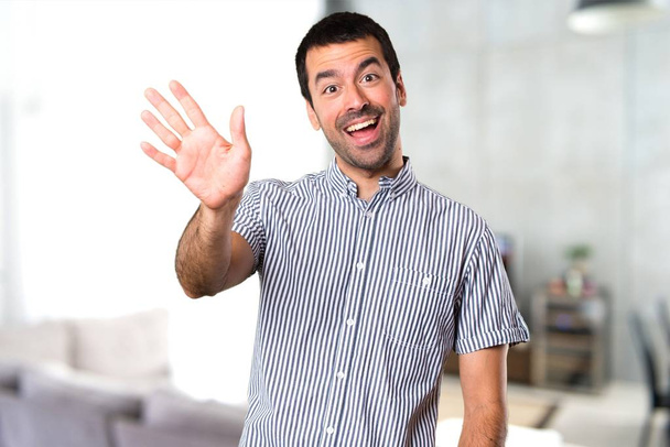 Hombre guapo saludando dentro de casa
 - Foto, Imagen