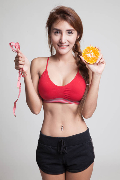 Asian healthy girl on diet with orange fruit and measuring tape. - Φωτογραφία, εικόνα