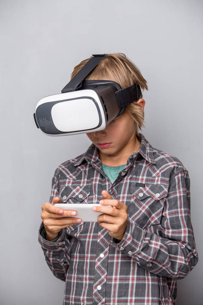 Boy in virtual reality glasses holdnig cell phone - Foto, imagen