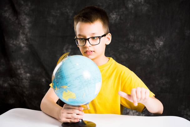 Kid looking at small globe on desk - Photo, Image