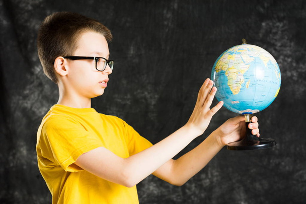 Junge dreht sich und blickt auf Globus - Foto, Bild