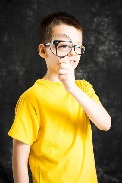 Boy looking through glasses and magnifying glass - Photo, Image