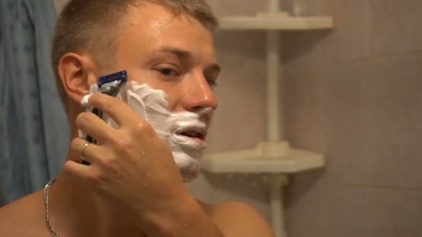 Adult man shaving with foam and manual razer - Filmati, video