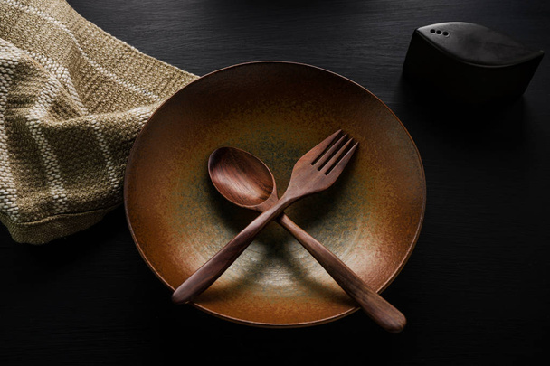 Piatto in ceramica (piatto) e cucchiaio di legno, forchetta di legno sul tavolo
 - Foto, immagini