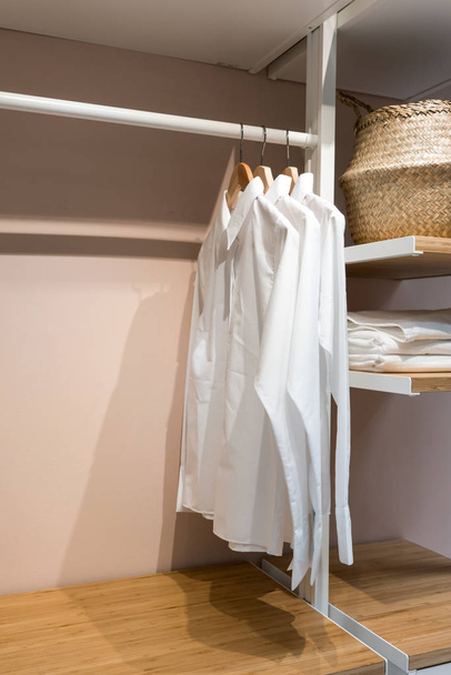 Chemises basiques blanches suspendues dans un placard avec tiroir
 - Photo, image