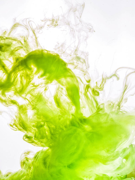 Ink swirl in water isolated on white background. The paint in the water. Soft dissemination a droplets of green ink in water close-up. Abstract background. Soft focus - Foto, afbeelding