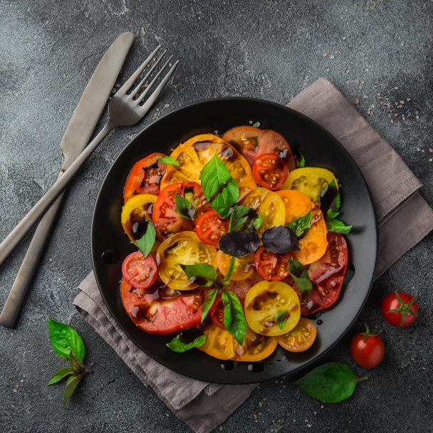 colorful tomatoes salad with basil and basamic vinegar - 写真・画像