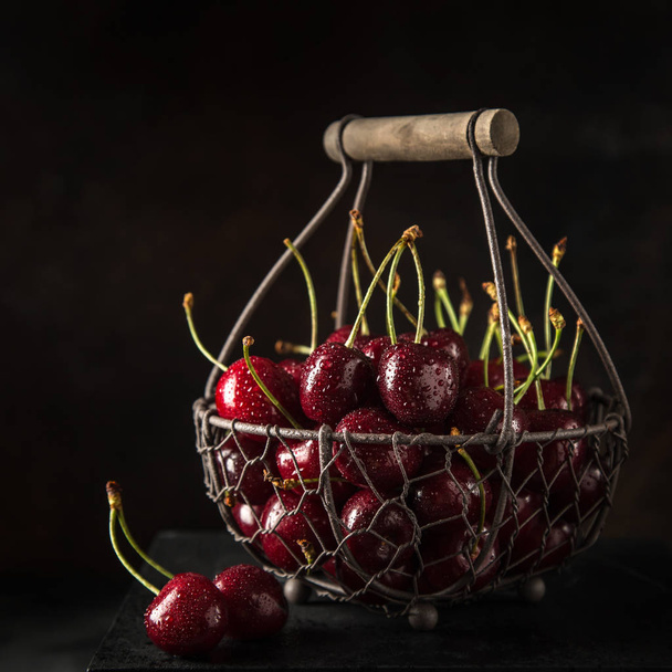 fresh sweet cherry on basket, selective focus, black background - 写真・画像