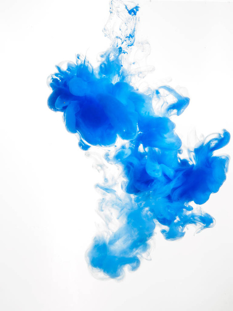 Tintenwirbel im Wasser isoliert auf weißem Hintergrund. die Farbe im Wasser. weiche Verteilung eines Tropfens blauer Tinte in Wasser Nahaufnahme. Abstrakter Hintergrund. Weicher Fokus - Foto, Bild