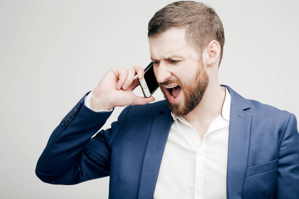 A young man in a business suit aggressively talking on the phone - Foto, Imagen