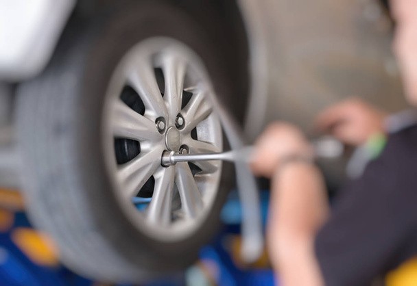 Mechanic changing car wheel in auto repair shop. serviceman wren - Фото, изображение