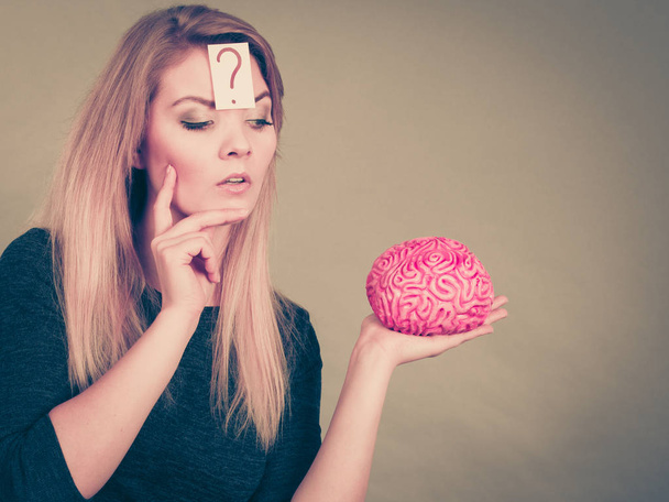 Woman thinking and holding fake brain - Valokuva, kuva