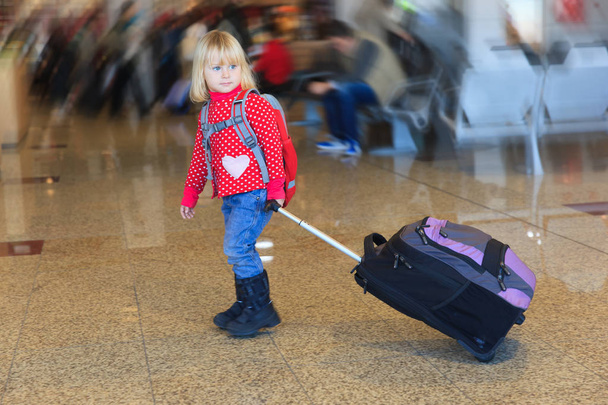 маленькая девочка с чемоданом путешествия в аэропорту
 - Фото, изображение