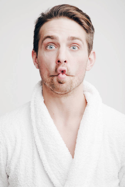 Emotions. Portrait of a young man in a bathrobe - Foto, Bild