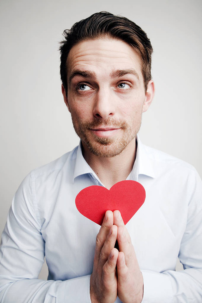 Valentine's Day. Emotions. Portrait of a man with a red heart in hand - Foto, Imagen