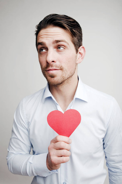 Valentine's Day. Emotions. Portrait of a man with a red heart in hand - Foto, Bild