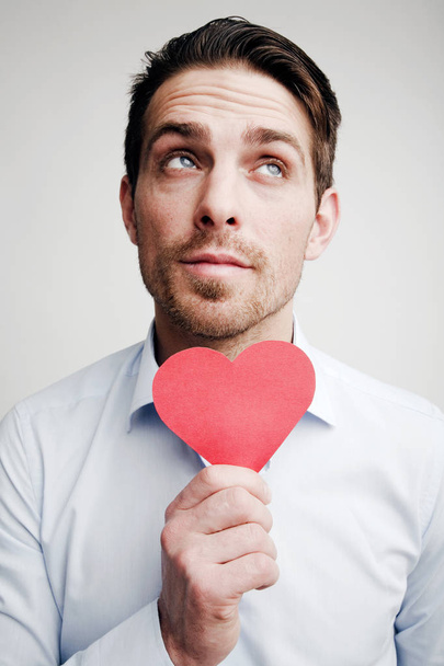 Valentine's Day. Emotions. Portrait of a man with a red heart in hand - Foto, Bild