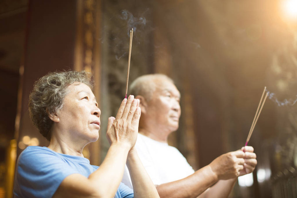 pareja de ancianos rezando buddha con palo de incienso en el templo
 - Foto, Imagen