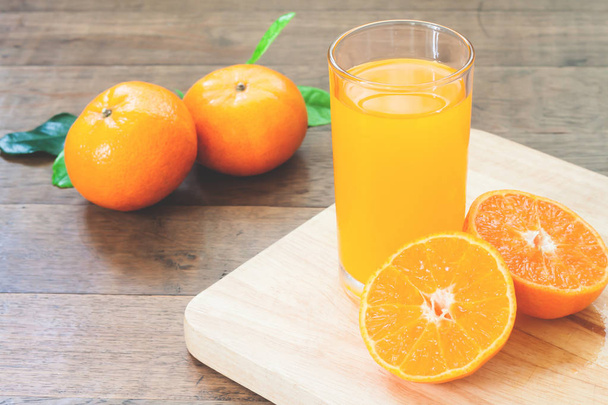 Χυμό πορτοκάλι με φρέσκα πορτοκάλια στο ξύλινο τραπέζι, το φθινόπωρο και το φθινόπωρο σεζόν - Φωτογραφία, εικόνα