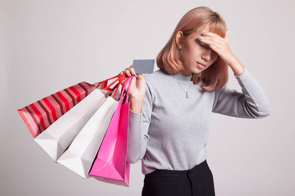Unhappy  young Asian woman with shopping bags and credit card. - 写真・画像