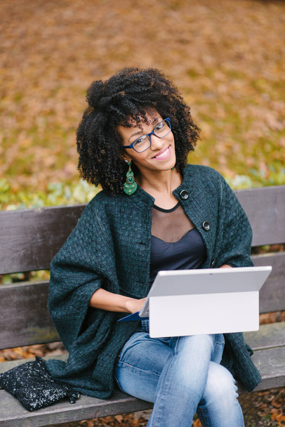Professional black woman working with laptop outside in autumn - Photo, image