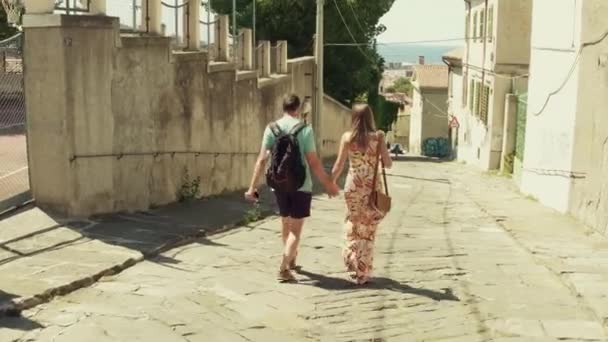 Young couple walking towards the sea in a Mediterranean town - Materiał filmowy, wideo