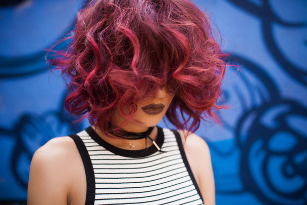 Street look of Fashion and Sexy woman with red curly hairstyle posing near graffiti wall - Photo, Image