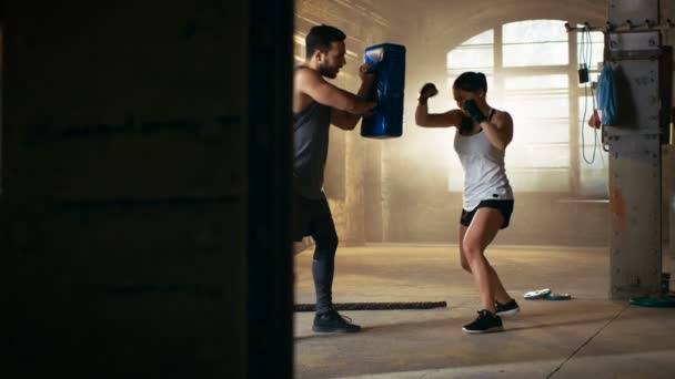 Donna atletica colpisce sacco da boxe che il suo partner / allenatore tiene. Lei è combattente professionista e si allena in una palestra
. - Filmati, video