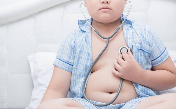 Zwaarlijvige vet jongen controleren hart door stethoscoop,  - Foto, afbeelding