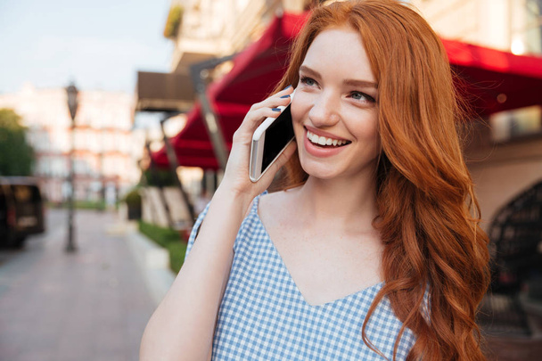 Smiling attractive girl with long hair talking on mobile phone - Photo, image