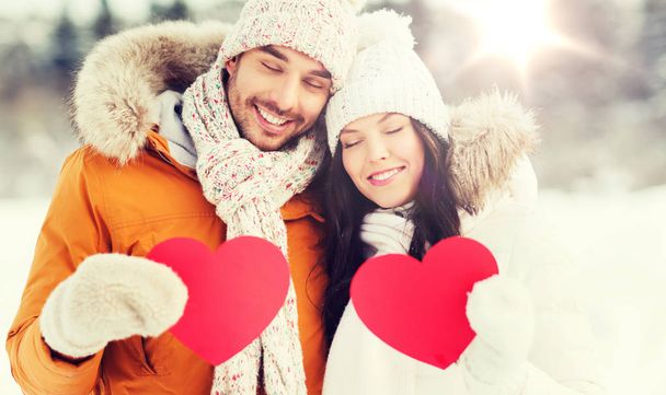 happy couple with red hearts over winter landscape - Foto, imagen