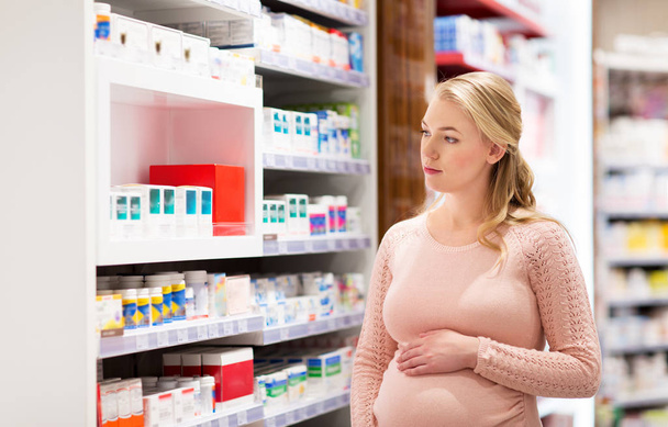 happy pregnant woman with medication at pharmacy - Фото, изображение
