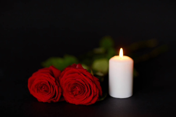 red roses and burning candle over black background - Fotó, kép