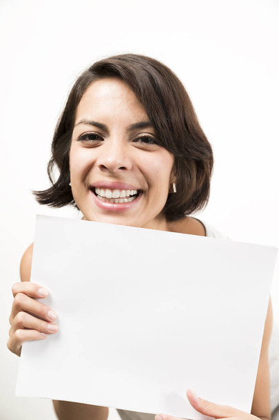 Beautiful young woman holding a blank sheet of paper. Space for your text. Isolated on white. - Фото, изображение
