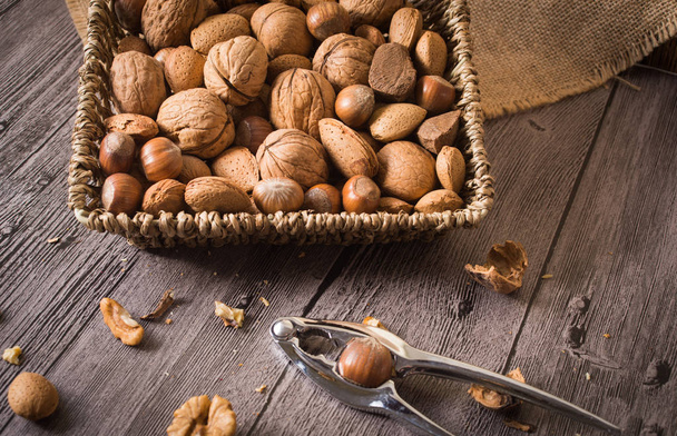 delicious assortment of nuts in a woven basket on wooden backgro - Foto, Bild